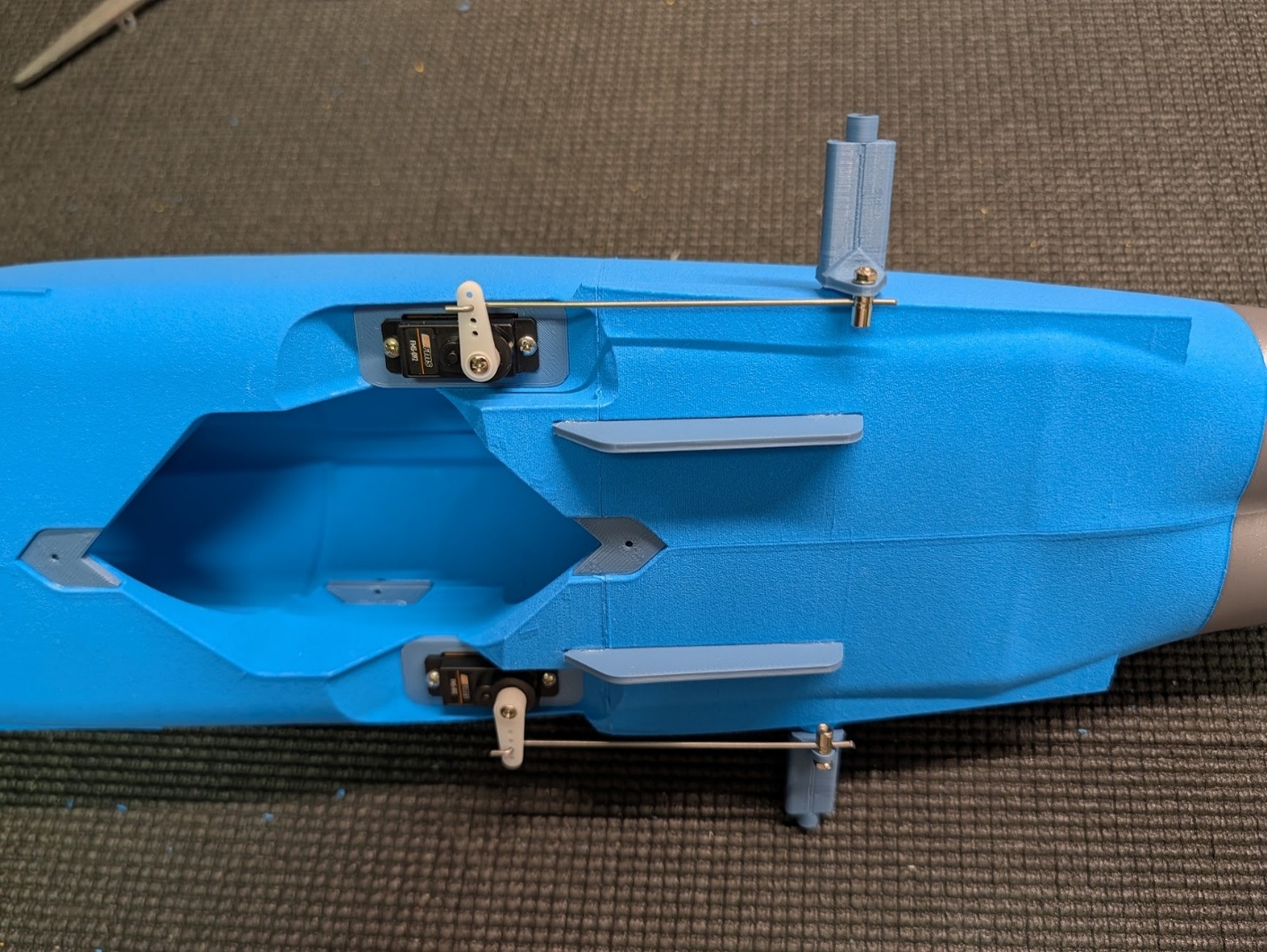Pushrods connected to servo arms and pivot blocks